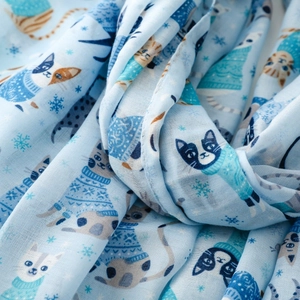 Close-up of light blue silk scarf featuring cute cartoon cats and snowflake patterns