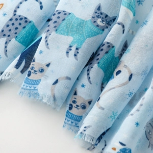 Close-up of cat paradise print on light blue scarf with frayed edges and snowflakes
