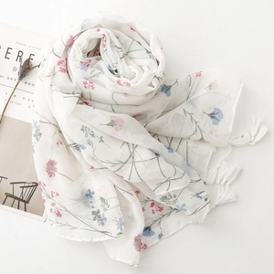 Detail of floral chiffon scarf with pink and blue blossoms and white fringed tassels