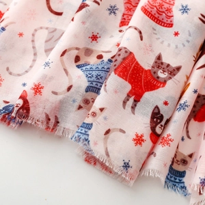 Detailed view of pink cat print scarf fabric with winter theme and frayed edges