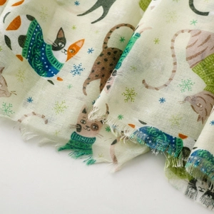 Detail of light green cat print scarf fabric with soft fringes and snowy patterns