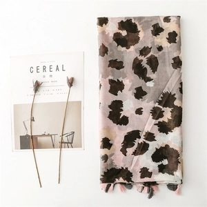 Lightweight leopard print shawl with fringe tassels and soft floral props in a flat lay