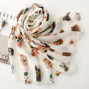 Detail of white scarf featuring cartoon dog prints and fringe edges on a white surface