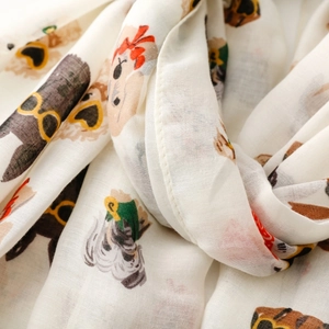 Detail of soft white scarf featuring playful cartoon dogs with sunglasses and bowties