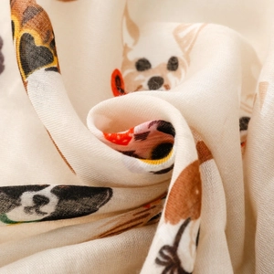 Detail of light beige scarf featuring cartoon dog prints on soft translucent fabric