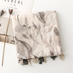 Detailed view of light beige scarf with floral print and decorative bicolor fringes