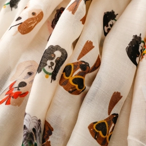 Detail shot of lightweight cream scarf fabric featuring cute dog prints and smooth texture