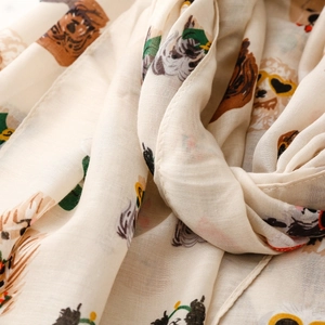 Detail of soft fabric scarf featuring diverse cartoon dog prints on beige background
