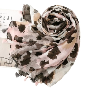 Lightweight leopard print scarf with tassels on white background with a magazine
