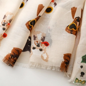 Detailed view of lightweight beige cotton scarf featuring cute cartoon dog prints and fringe