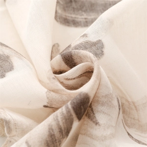 Macro shot of cream linen-feel scarf fabric with floral prints and delicate fringe edge