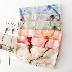 Flat lay of multiple colorful watercolor floral printed scarves in vibrant various tones