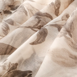 Macro detail of breathable beige scarf fabric featuring a vintage brown leaf pattern