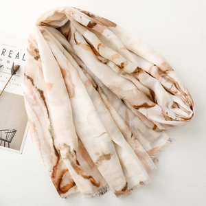 Detail of soft cream scarf with brown abstract marble pattern and frayed edges