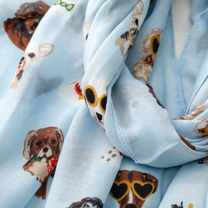 Close-up of light blue silk scarf featuring artistic cartoon dog prints and soft texture
