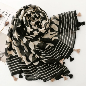 Detail of artistic thin scarf with geometric patterns and fringe on white surface