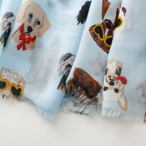 Detail of light blue scarf featuring cartoon dog prints and natural frayed edges