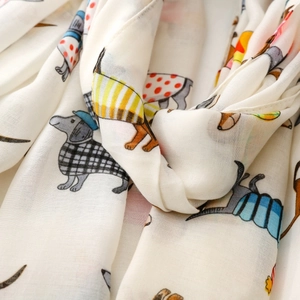 Close-up of lightweight white scarf featuring playful cartoon dachshund prints and soft texture