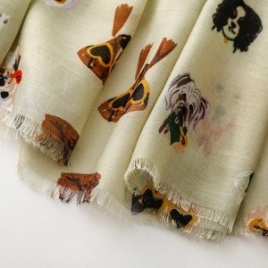 Detail of light green scarf featuring cute dog illustrations with frayed fringe edges