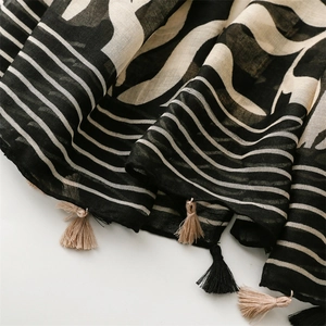 Detail shot of lightweight floral scarf with decorative black and beige tassels