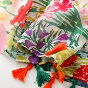Macro shot of lightweight voile scarf featuring floral prints and vibrant orange tassels