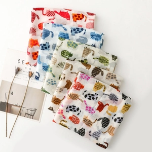 Detail of colorful cat print cotton scarves stacked neatly with lifestyle props