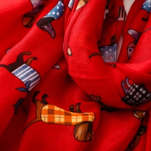 Detail of red dachshund print scarf showing soft fabric folds and cartoon dog pattern