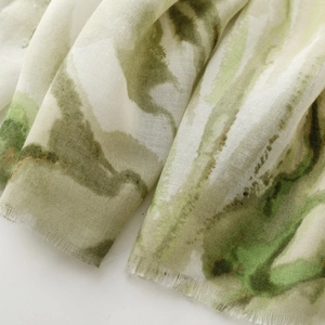 Detail showing green watercolor floral print on light scarf with frayed edge trim