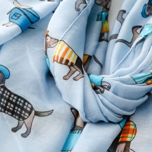 Detail of light blue dachshund print scarf showing soft fabric texture and cartoon dogs
