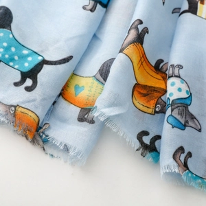 Macro detail of cartoon dog print scarf showing fine fabric texture and raw fringe edges