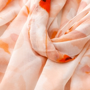Detailed macro view of soft orange floral print fabric on a lightweight cotton silk scarf