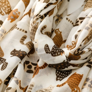 Detailed close-up of soft white cotton scarf with playful brown cat patterns and texture