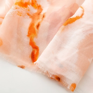 Detail of peach cotton scarf with orange ink painting patterns and fringed edges
