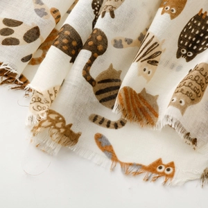 Detail view of cotton scarf featuring cute cat patterns and soft frayed fringe edges