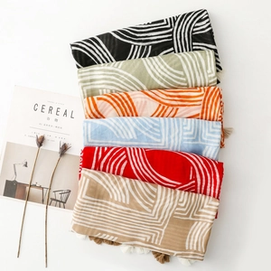 Detail of linen-feel scarves with geometric lines and tassel trim in multiple colors