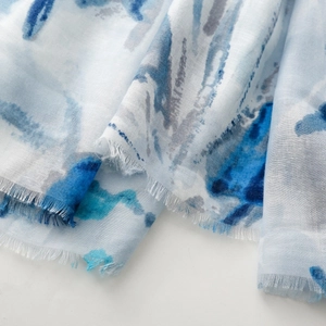 Detail of light blue ink painting scarf with fine fringe edges and soft fabric texture