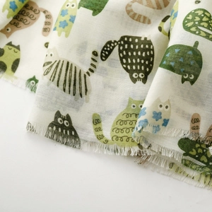 Detail of soft cotton scarf featuring playful cartoon cat prints and natural frayed edges