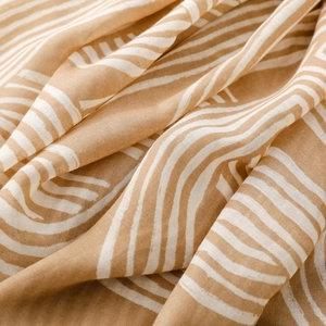 Detail showing soft cotton linen fabric texture with white wave pattern on warm ginger scarf