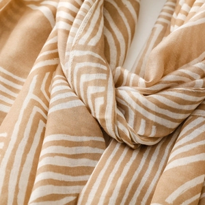 Detailed close-up of camel and cream geometric stripe scarf with soft fringe texture