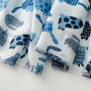 Detailed view of soft cotton scarf fabric with artistic blue cat print and drape