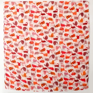 Close-up of lightweight white scarf featuring colorful cartoon cat patterns in warm tones