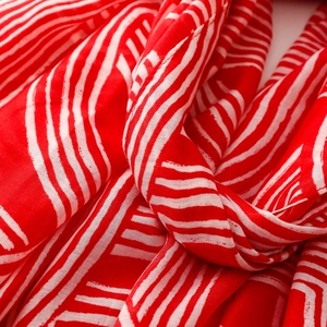 Close-up of red and white striped cotton linen scarf fabric with soft woven textures