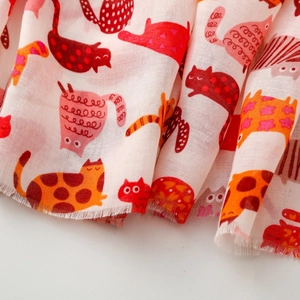 Detail of soft fabric scarf featuring playful cat prints and delicate fringed edges