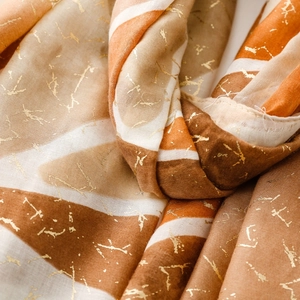 Dettaglio di sciarpa in cotone e lino con stampa in lamina d'oro e design geometrico