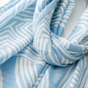 Close-up of lightweight blue scarf with white abstract geometric line patterns and soft texture