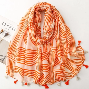 Detail of soft scarf with orange wavy patterns and matching fringe tassels on white background