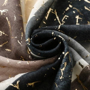 Dettaglio di sciarpa in cotone e lino con eleganti motivi triangolari dorati