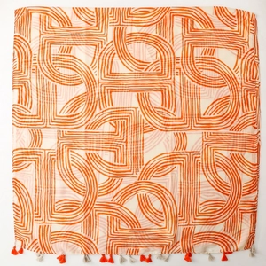 Close-up of geometric orange stripes on cream scarf with decorative tassels