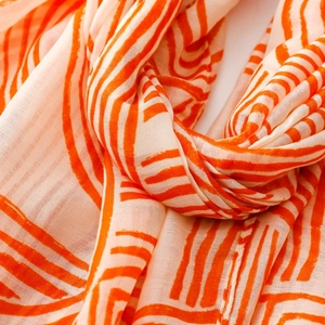 Macro shot of soft pink cotton linen scarf featuring bold orange geometric line patterns