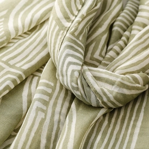 Detail shot of green and beige striped cotton-linen scarf with soft woven fabric texture